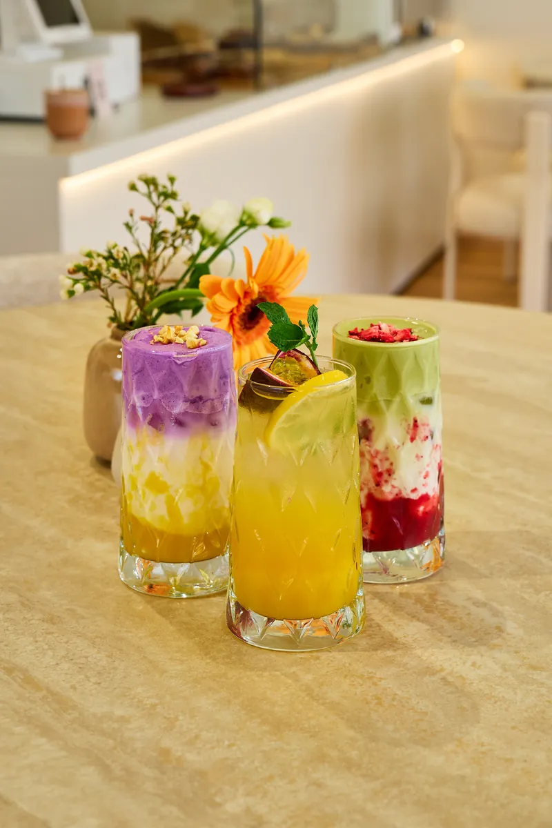 Drei bunte Drinks mit Blumen vor der Theke