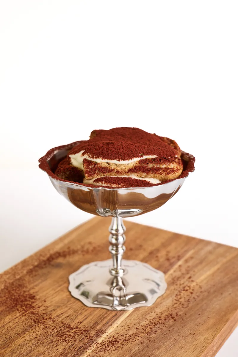 Tiramisu im Silberbecher auf Holzbrett